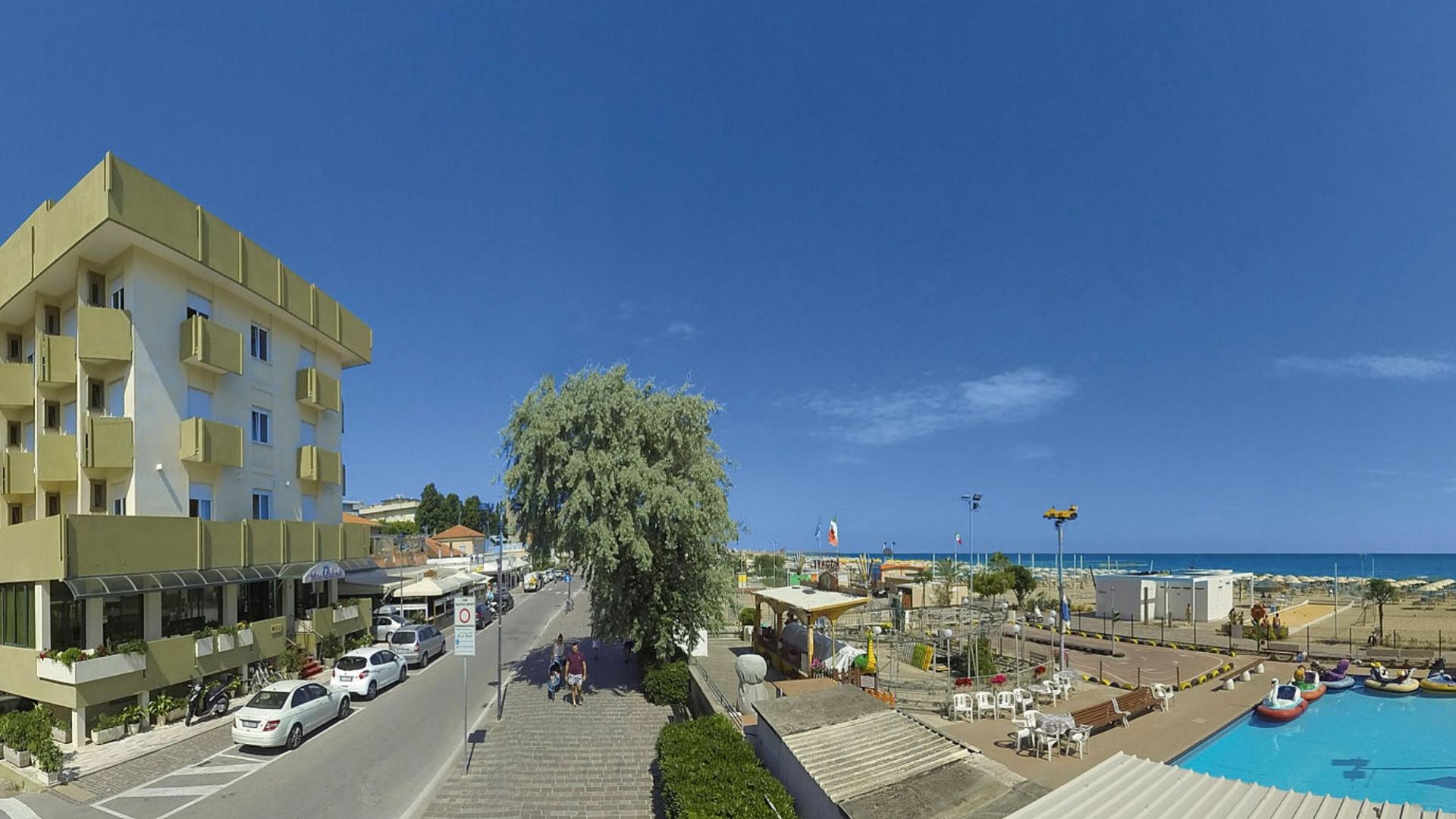 Vista mare con edificio, strada e parco giochi acquatico sulla spiaggia.