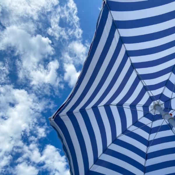 Ombrellone a righe blu e bianche sotto un cielo con nuvole.
