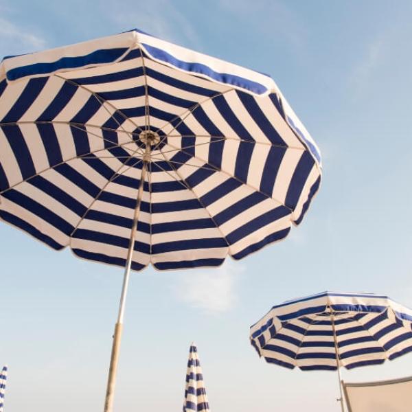 Ombrelloni a righe blu e bianche su una spiaggia sotto un cielo sereno.