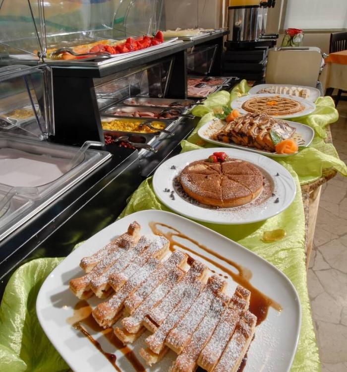 Buffet dolce con waffle, pancake e frutta fresca in esposizione.