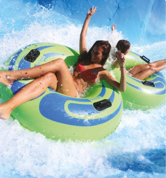 Due persone si divertono su ciambelle gonfiabili in uno scivolo d'acqua.